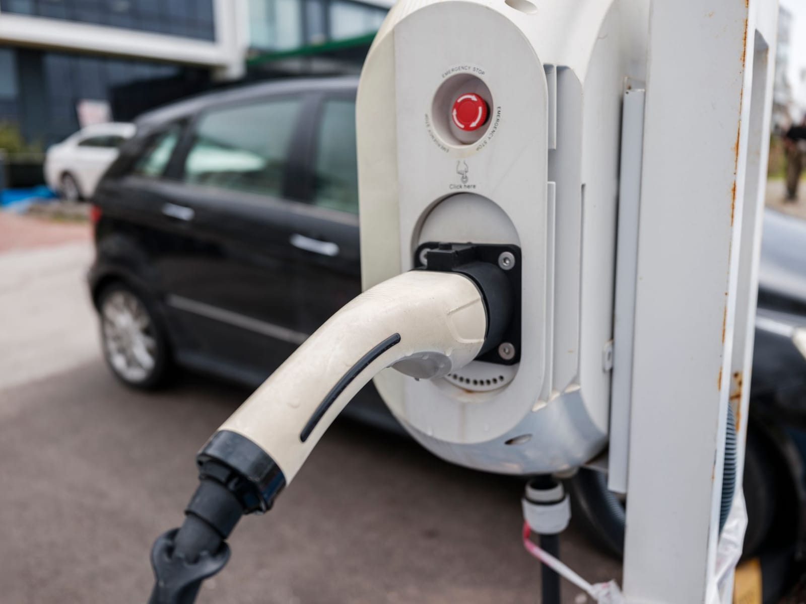 Wall-mounted commercial EV charger with a Type 2 connector plugged into a car